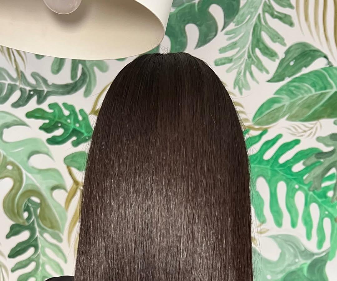 Cabello castaño liso frente a hojas tropicales, visto de espaldas