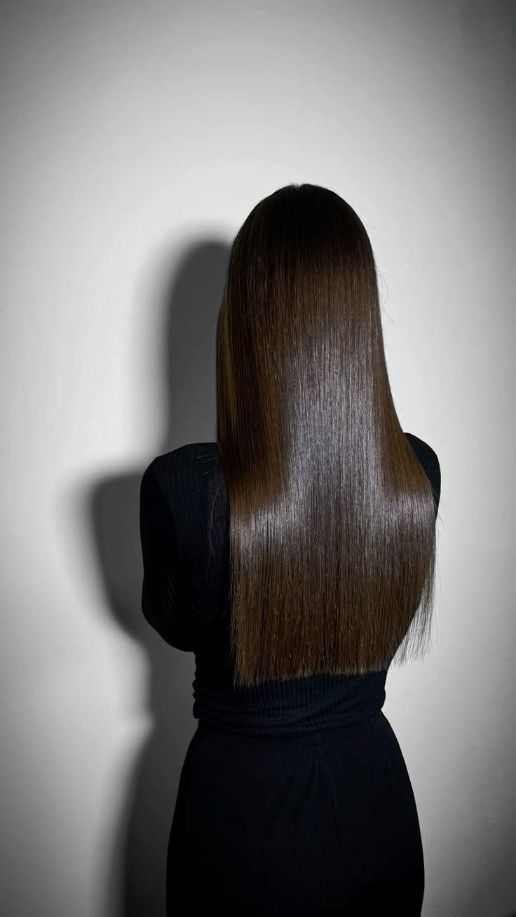 Cabello largo, oscuro y liso sobre fondo gris, visto de espaldas
